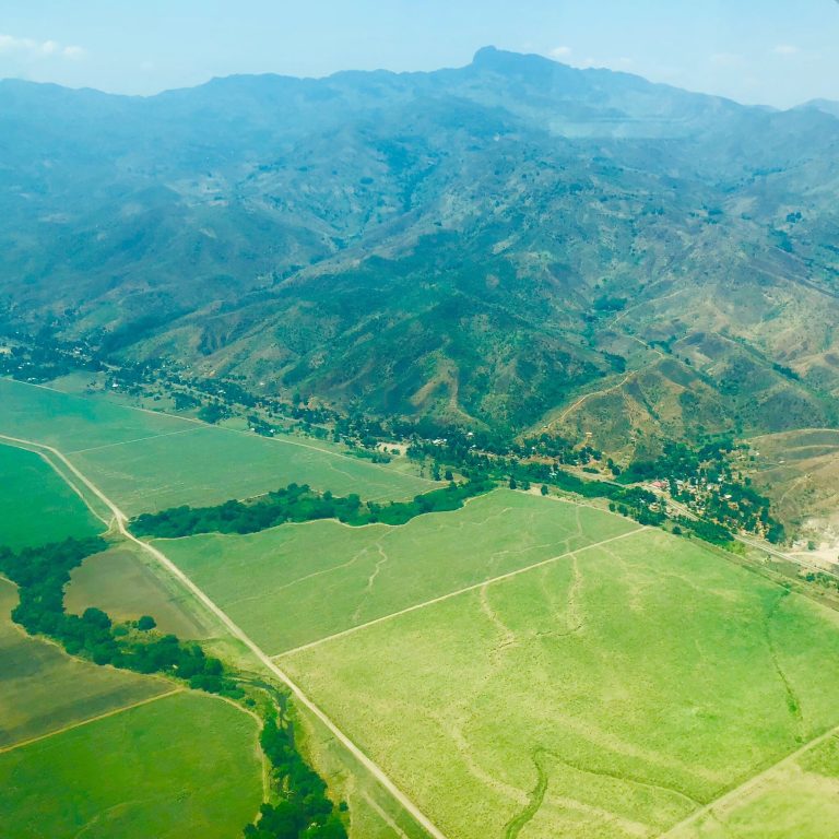 Aerial view of farmland below a forested mountain range, Udzungwa Mountains National Park