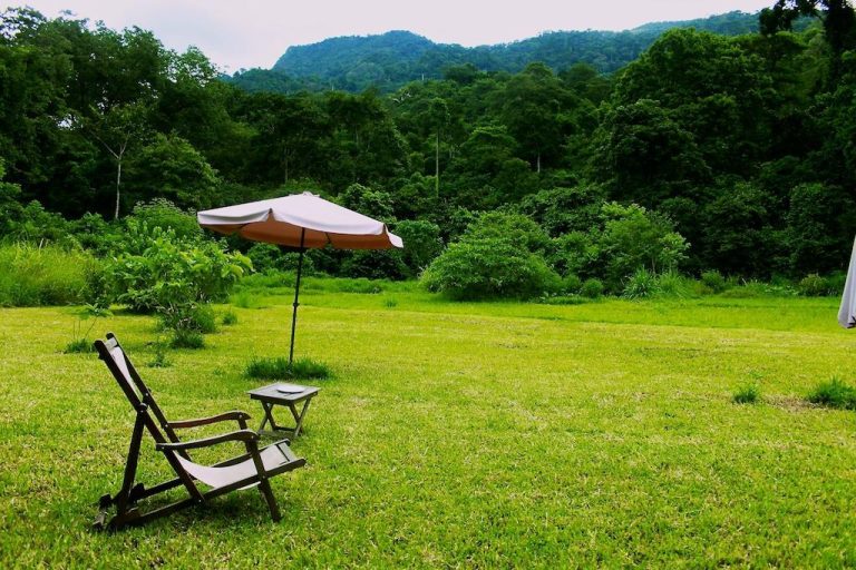 Lawn deckchair under a parasol facing forested hills, Udzungwa Mountains National Park