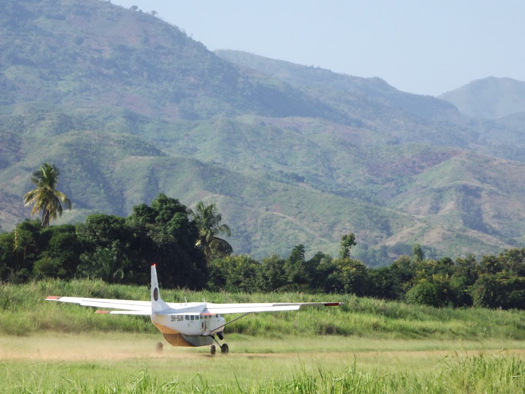 Light aircraft on a grass airstrip below the mountains, Udzungwa Mountains National Park