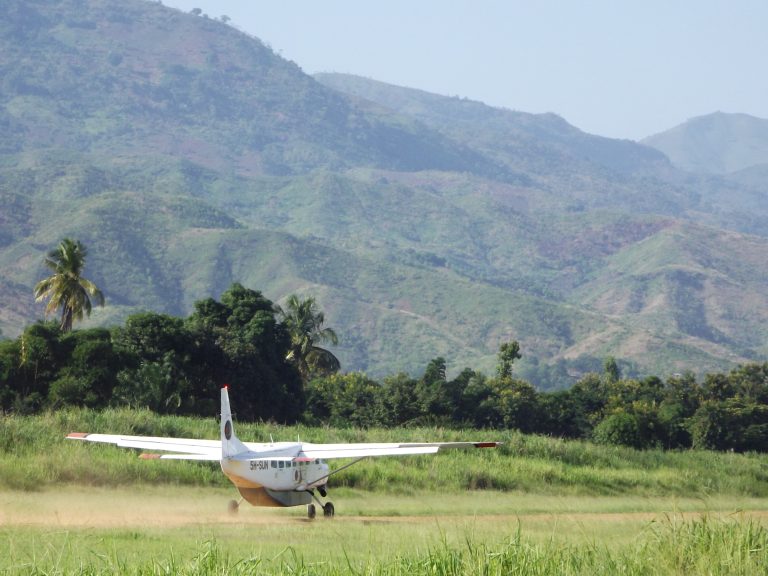 Light aircraft on a grass airstrip below the mountains, Udzungwa Mountains National Park