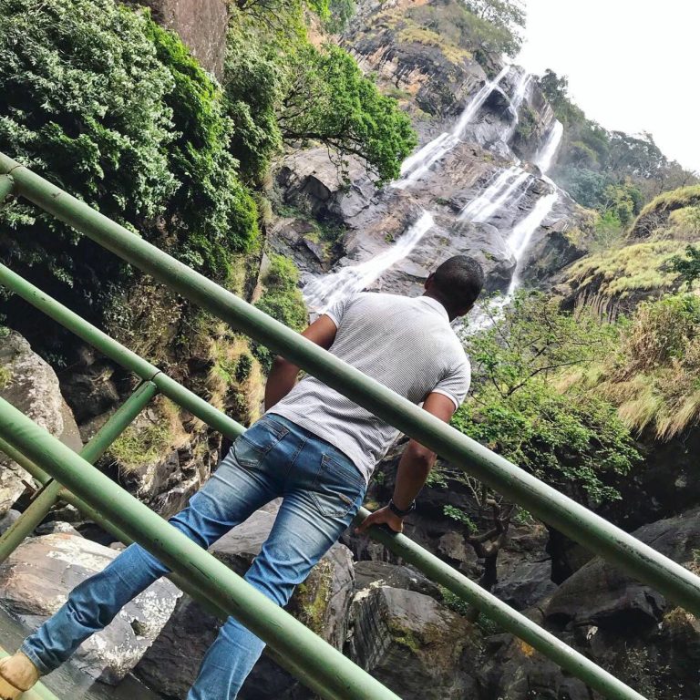 Man at a green railing viewing the tall falls, Udzungwa Mountains National Park