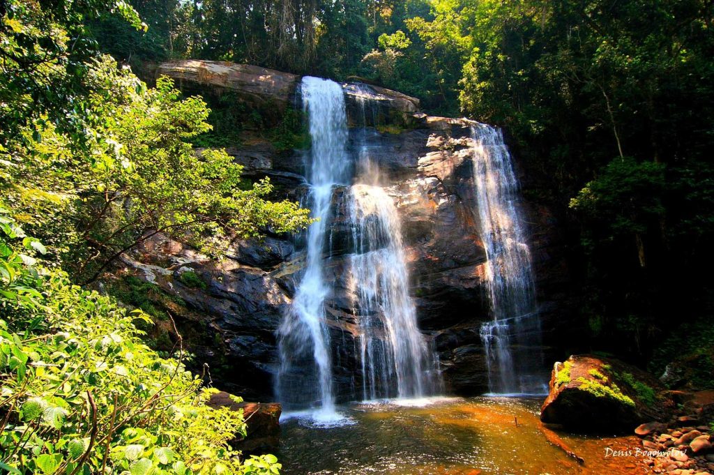 Multi-strand waterfall falling into a shallow brown pool, Udzungwa Mountains National Park