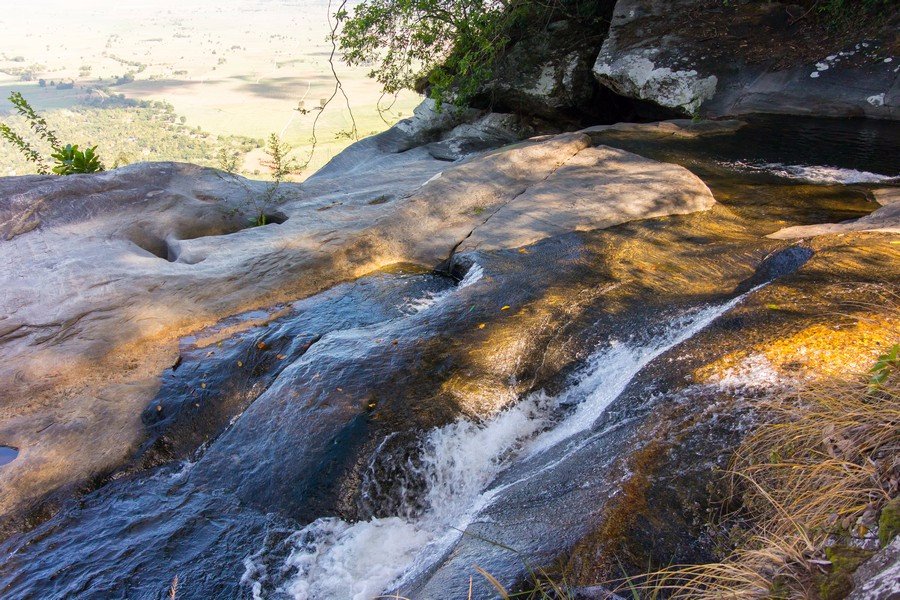 Stream sliding over sunlit rock slabs above the plains, Udzungwa Mountains National Park