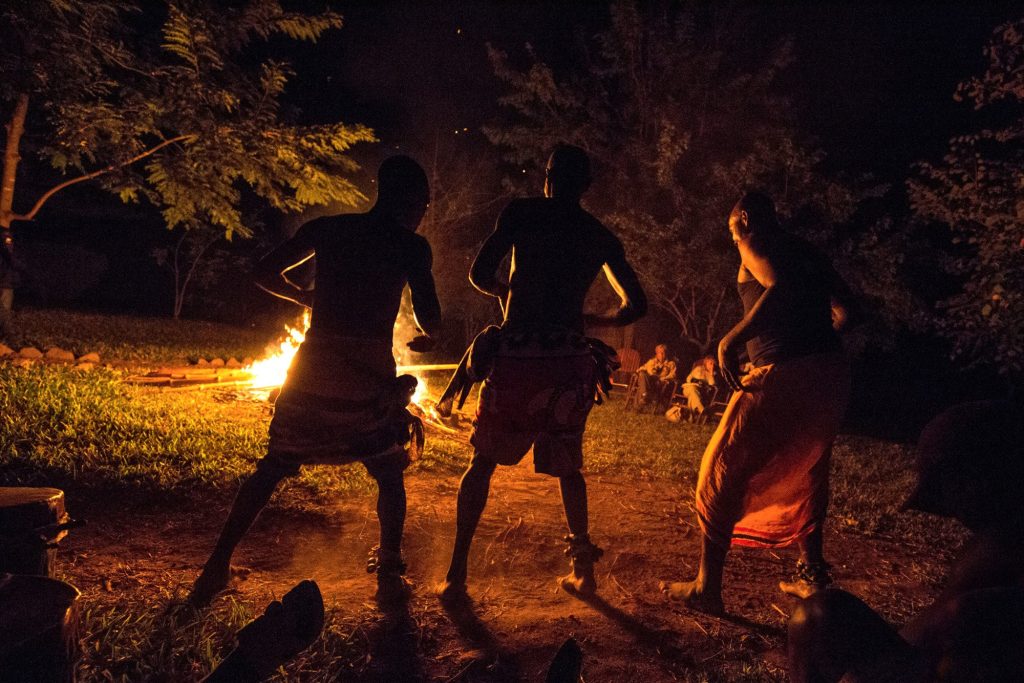 Three dancers performing by a campfire at night, Udzungwa Mountains National Park