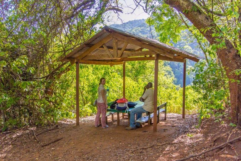 Two hikers resting at a wooden trail shelter, Udzungwa Mountains National Park