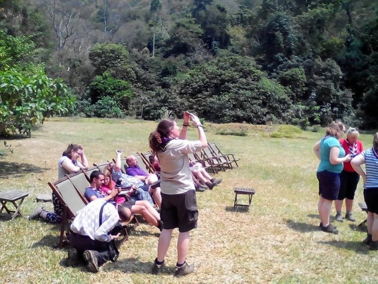Woman photographing guests in deckchairs on the lawn, Udzungwa Mountains National Park