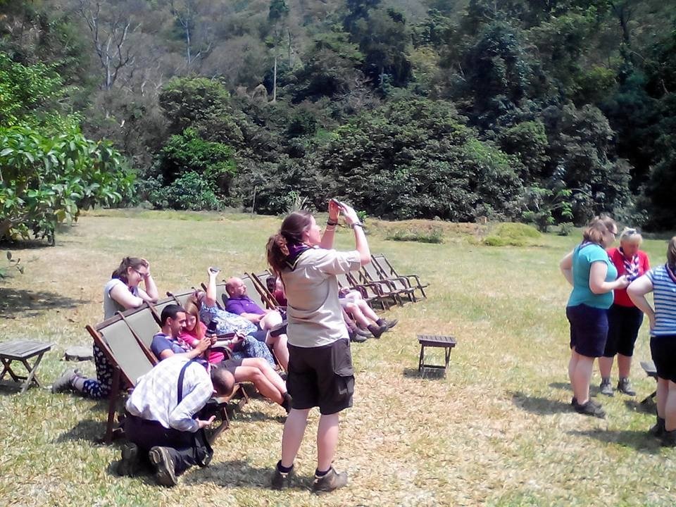 Woman photographing guests in deckchairs on the lawn, Udzungwa Mountains National Park